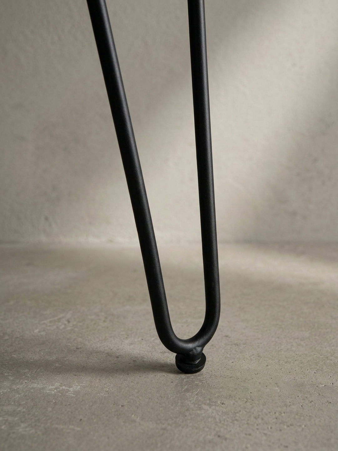 Detailaufnahme eines schwarzen Haarnadelbeins des Schreibtischs, das den Mid-Century-inspirierten Charakter des Designs unterstreicht._