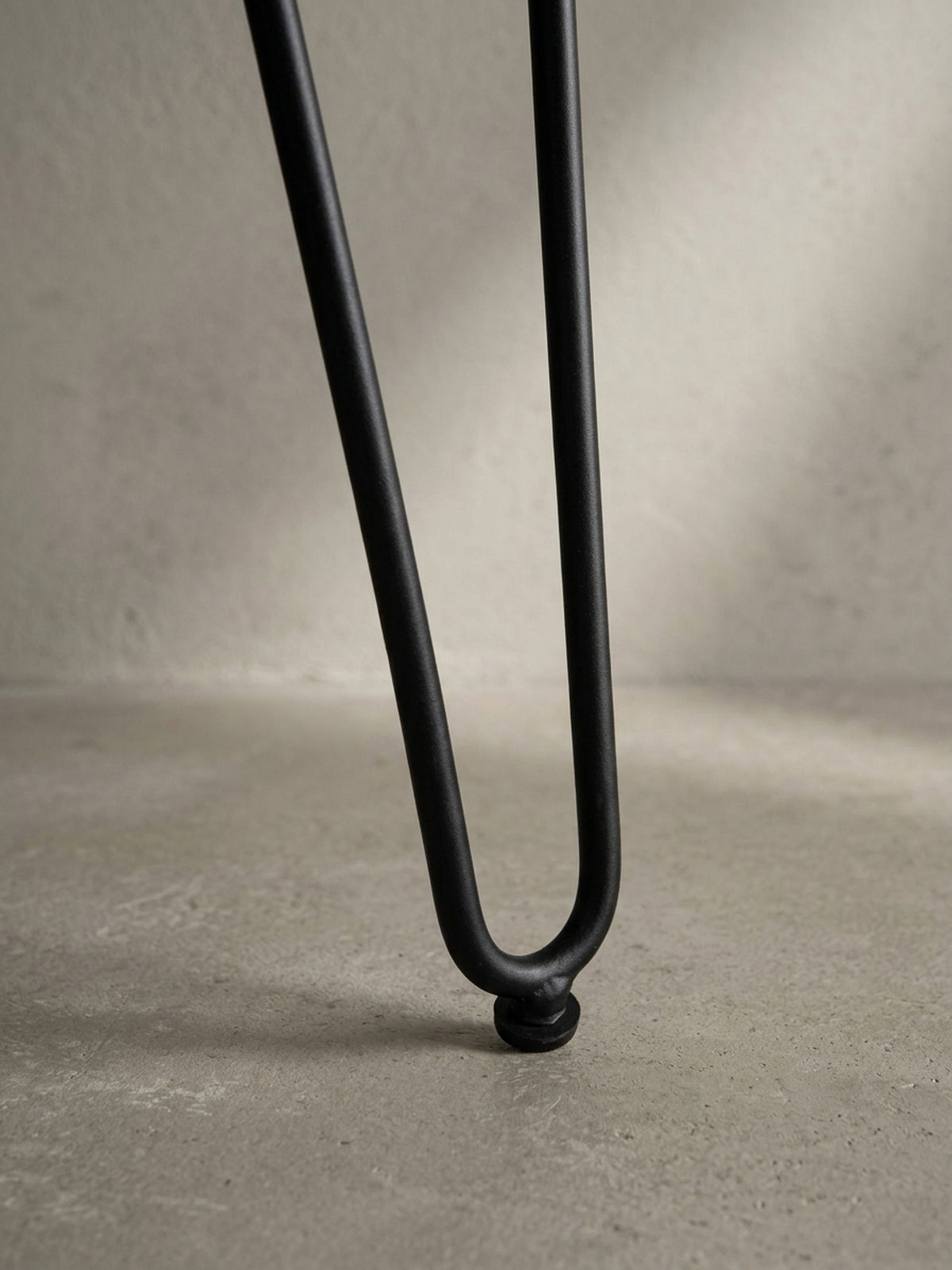Detailaufnahme eines schwarzen Haarnadelbeins des Schreibtischs, das den Mid-Century-inspirierten Charakter des Designs unterstreicht.