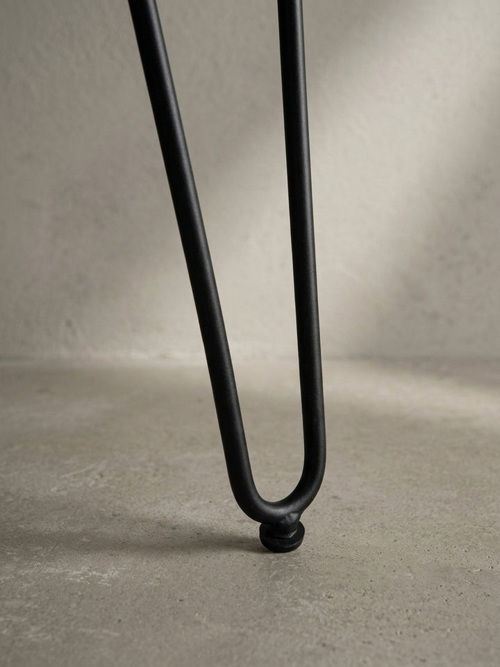 Detailaufnahme eines schwarzen Haarnadelbeins des Schreibtischs, das den Mid-Century-inspirierten Charakter des Designs unterstreicht._