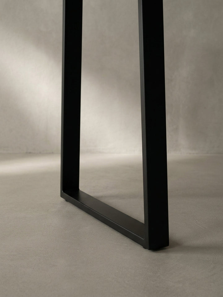 Detailaufnahme des schwarzen, pulverbeschichteten Trapezbeins, das die hochwertige Verarbeitung und die moderne, geometrische Form des Metallgestells zeigt._
