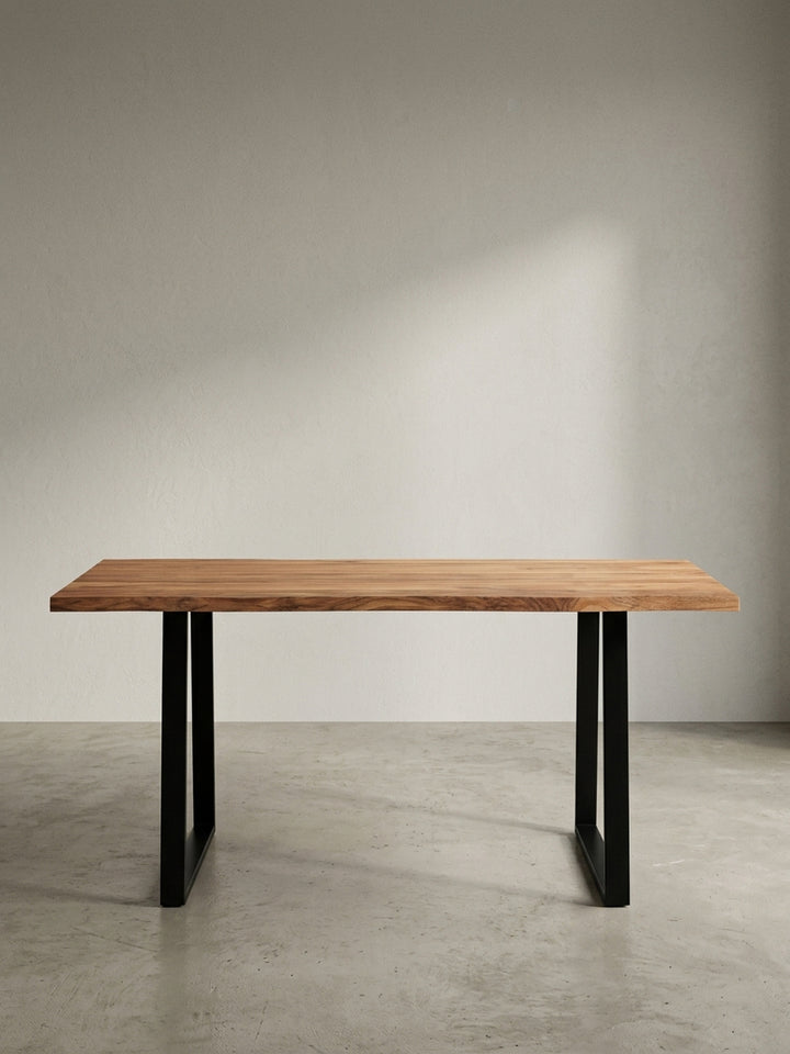 Frontansicht des Schreibtisches aus Akazie Massivholz, 160 cm breit, mit markanter Baumkante und stabilen, schwarzen Metall-Trapezbeinen auf weißem Hintergrund._