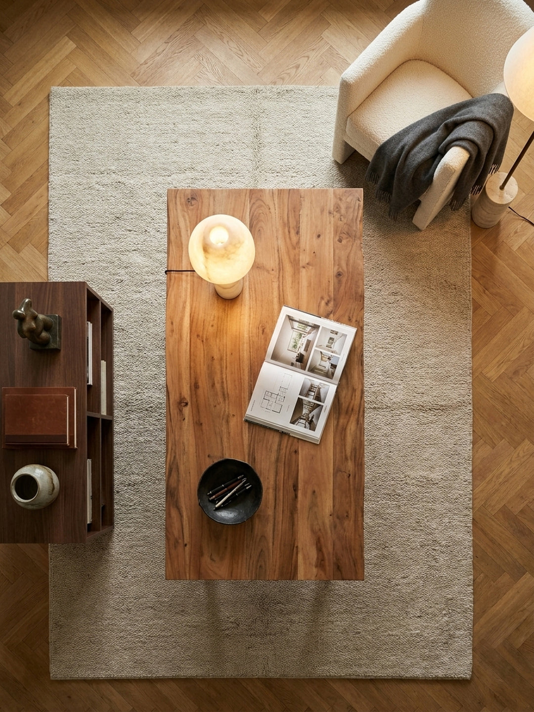 Draufsicht auf den Homeoffice-Arbeitsplatz mit dem Akazien-Holztisch und schwarzen Metallbeinen, arrangiert auf einem hellen Wollteppich._