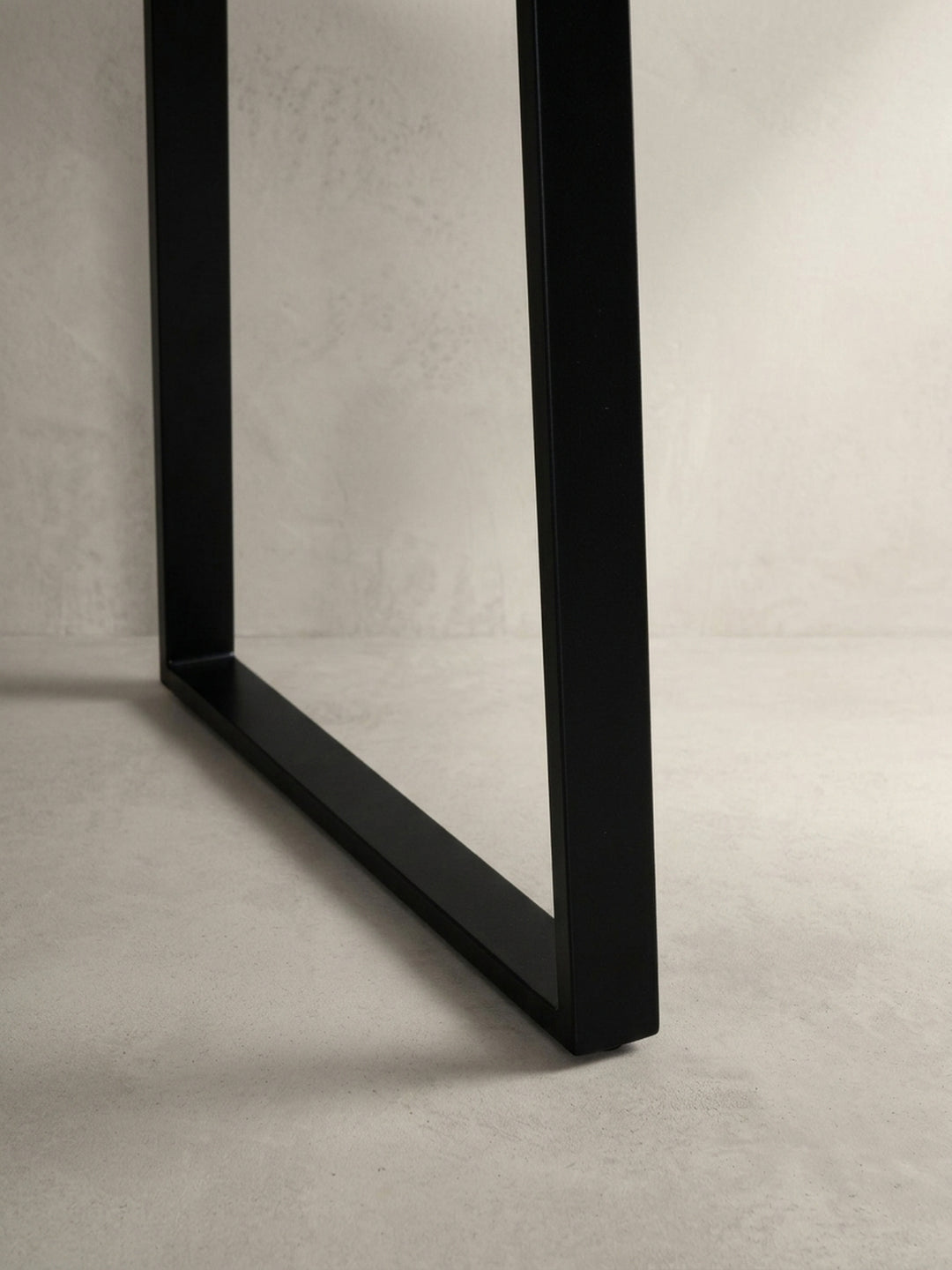 Detailaufnahme des schwarzen, pulverbeschichteten Trapezbeins des Schreibtisches, das für einen sicheren und modernen Stand auf jedem Bodenbelag sorgt._