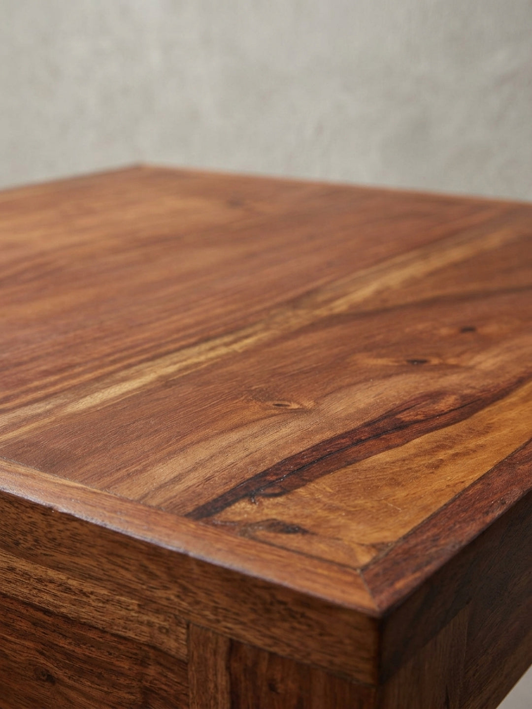 Schreibtisch für das Home Office aus einer dynamischen Perspektive, die das Zusammenspiel von warmem Sheeshamholz und kühlem Chrom hervorhebt._