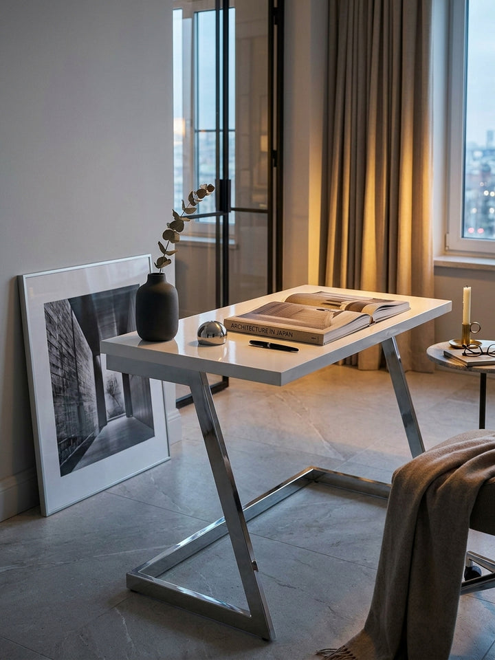 Weißer Design-Schreibtisch stilvoll dekoriert mit Architekturbüchern und einer Skulptur aus mattem Stahl am großen Fenster._