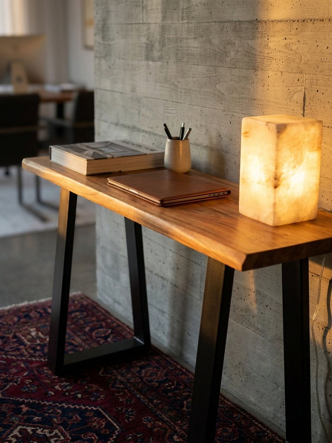 Vignette auf einem Massivholz-Schreibtisch: Ein Laptop neben einer Alabaster-Tischlampe und einem Stapel Designbücher, die eine inspirierende Arbeitsatmosphäre schaffen._