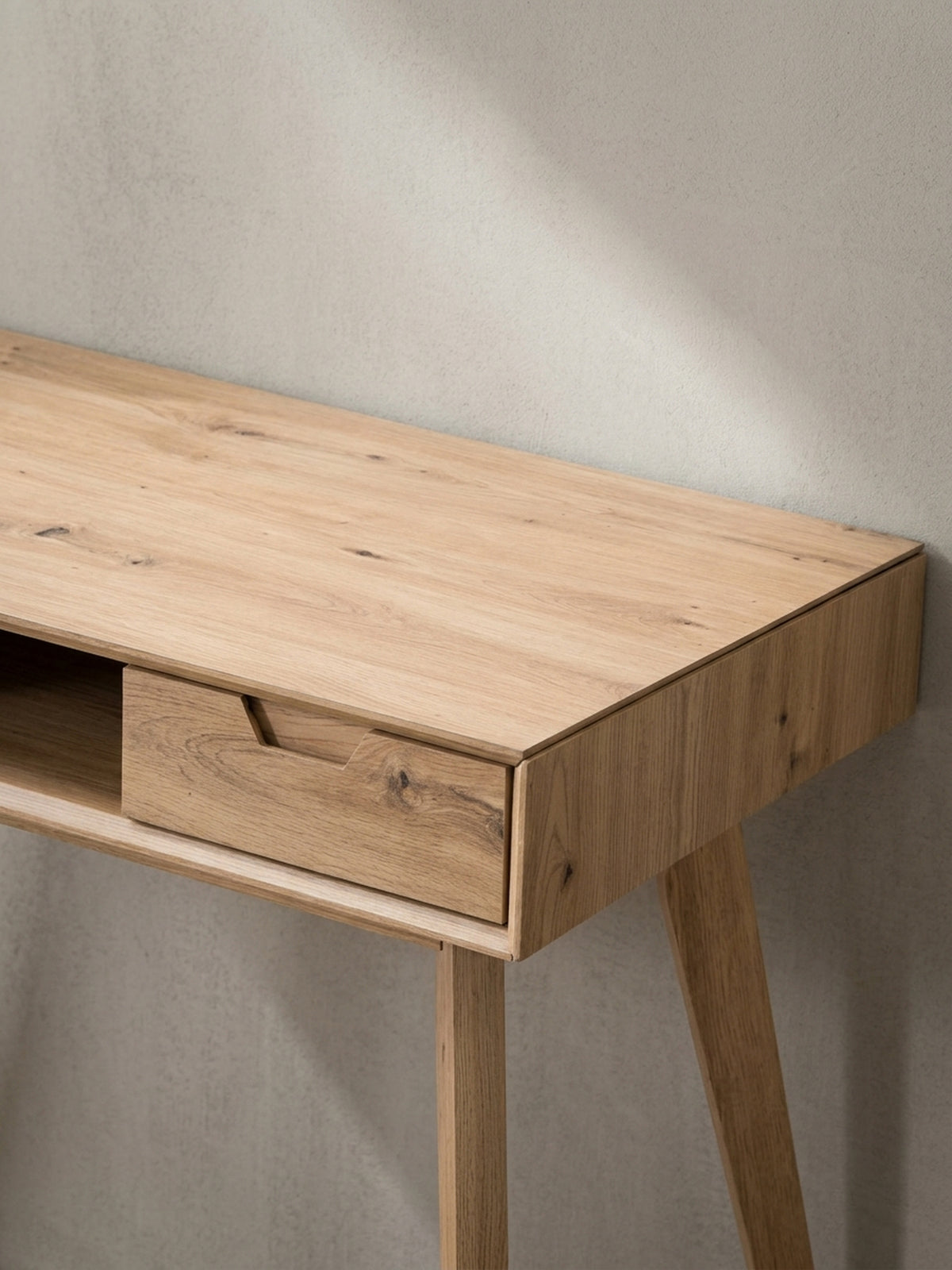 Der Design-Schreibtisch aus einer alternativen Perspektive, die die grifflosen Schubladen und die klare Linienführung betont.