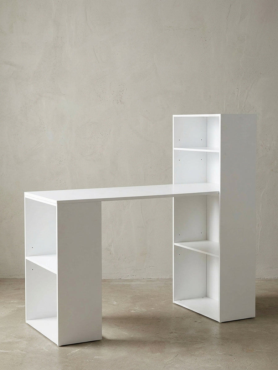 Moderner Schreibtisch mit integriertem Regal in mattem Weiß vor neutralem Hintergrund. Frontalansicht zeigt die asymmetrische Form mit 53 cm Tiefe und viel Stauraum._