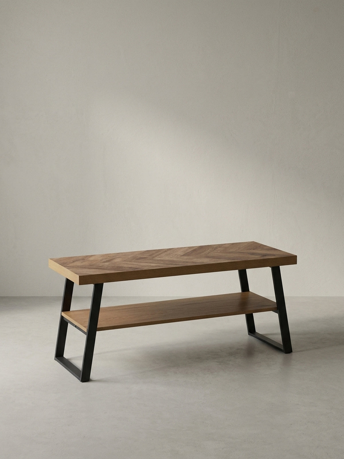 Schräge 3/4-Perspektive der Garderobenbank, die die Tiefe der Sitzfläche von 40 cm und das schlanke, schwarze Metallgestell zeigt._
