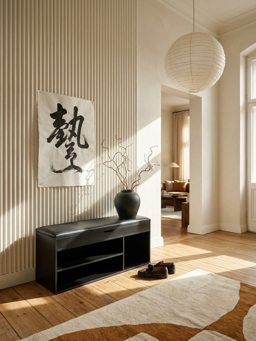 Moderne schwarze Schuhbank mit gepolsterter Kunstleder-Sitzfläche im minimalistisch gestalteten Flur mit heller Holzdielen und texturierter Wand._