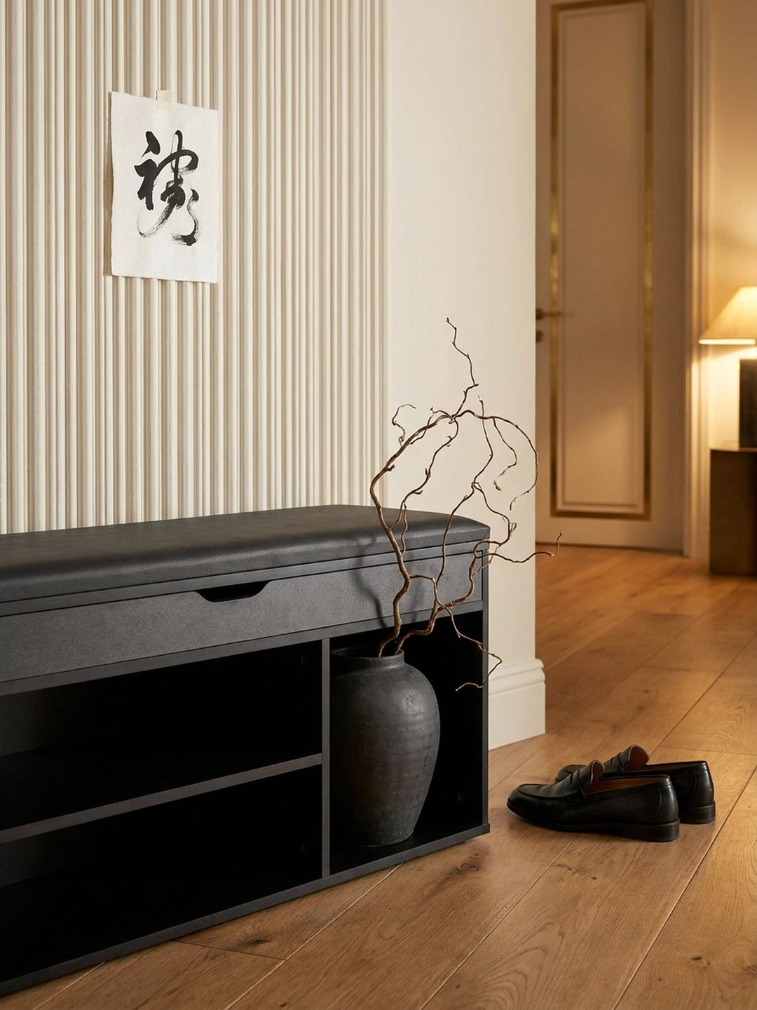 Styling-Detail einer schmalen Sitzbank im Flur, in deren offenem Fach ein Korb mit Wollschals für eine wohnliche Atmosphäre sorgt._