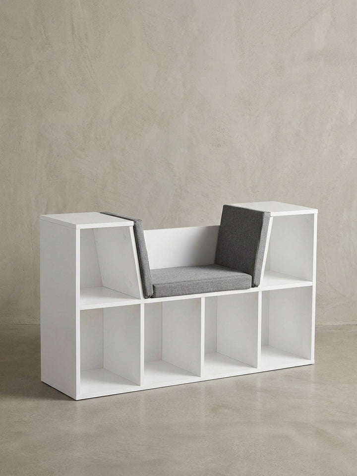 Freigestellte Frontansicht der weißen Sitzbank mit 6 Fächern und grauer Sitzauflage. Das klare, geometrische Design und die Kombination aus Regal und Bank werden deutlich._