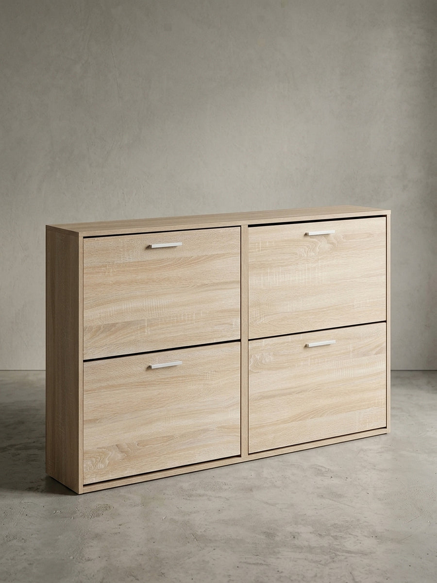 Vorderansicht der hellen Schuhkommode in Eiche Sonoma mit 4 geräumigen Kippfächern. Das 120 cm breite Schuhregal aus Holz steht freigestellt vor einem weißen Hintergrund._