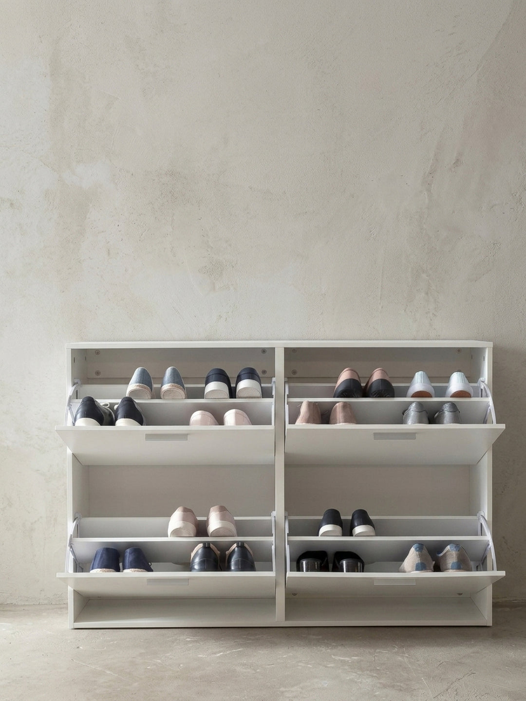 Nahaufnahme der edlen Aluminiumgriffe am weißen Schuhschrank. Die minimalistischen, geradlinigen Beschläge heben sich dezent von der mattweißen Holz-Oberfläche der Flurkommode ab._