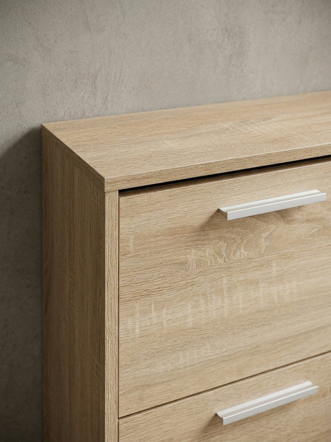 Nahaufnahme der edlen Aluminiumgriffe auf der Holzstruktur des Schuhschranks. Der moderne Kontrast zwischen kühlem Metall und warmer Sonoma Eiche der Flurkommode._
