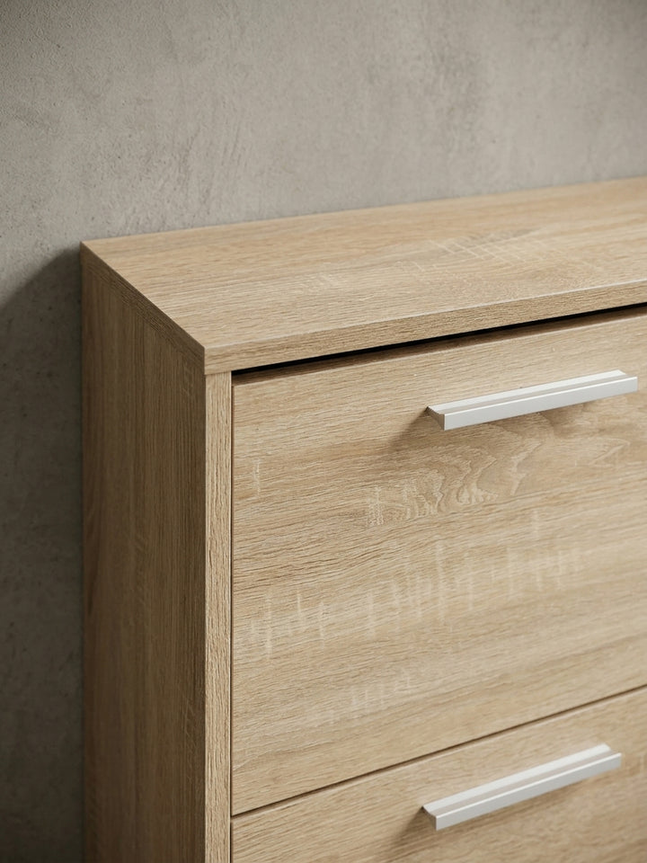 Nahaufnahme der edlen Aluminiumgriffe auf der Holzstruktur des Schuhschranks. Der moderne Kontrast zwischen kühlem Metall und warmer Sonoma Eiche der Flurkommode._