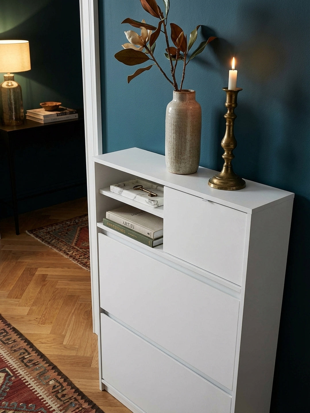 Ein stilvolles Arrangement auf dem weißen Schuhschrank: eine Keramikvase mit Trockenblumen und eine Schale für Schlüssel schmücken den Flur._