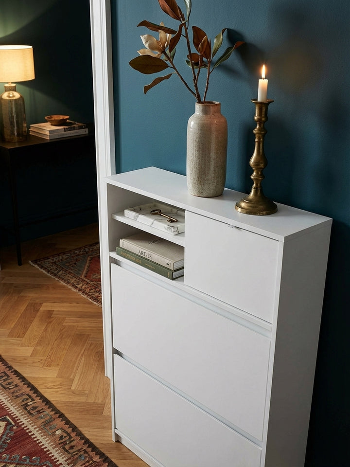 Ein stilvolles Arrangement auf dem weißen Schuhschrank: eine Keramikvase mit Trockenblumen und eine Schale für Schlüssel schmücken den Flur._