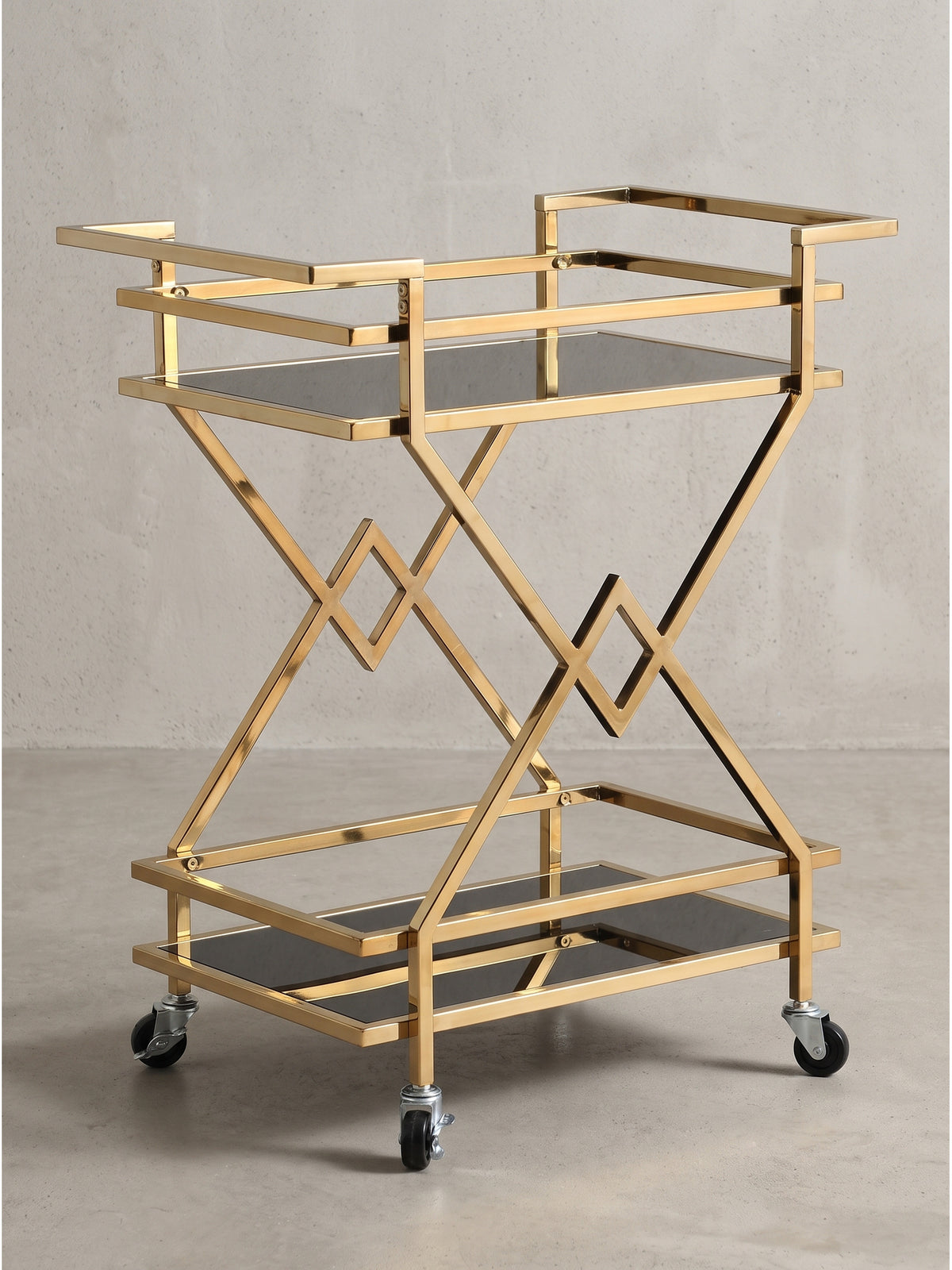 Geometrischer Servierwagen aus Metall in Gold und schwarzem Sicherheitsglas in der Frontansicht mit seitlichen Griffen.