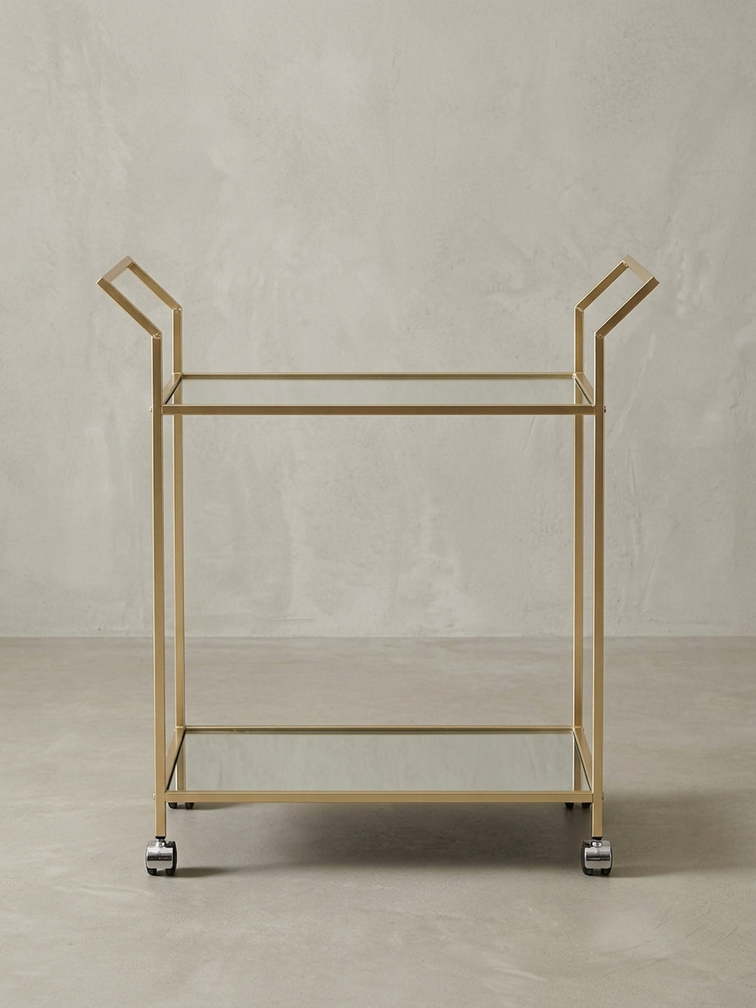Gesamtansicht des eleganten Servierwagens, der die Kombination aus goldfarbenem Stahl und spiegelnden Glasplatten perfekt zur Geltung bringt._