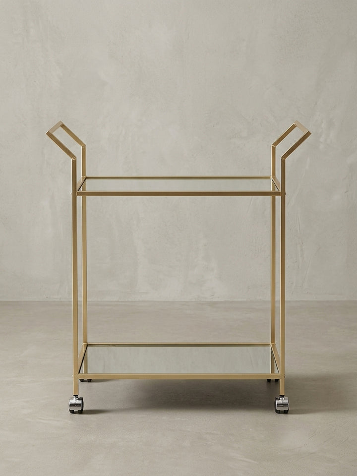 Gesamtansicht des eleganten Servierwagens, der die Kombination aus goldfarbenem Stahl und spiegelnden Glasplatten perfekt zur Geltung bringt._