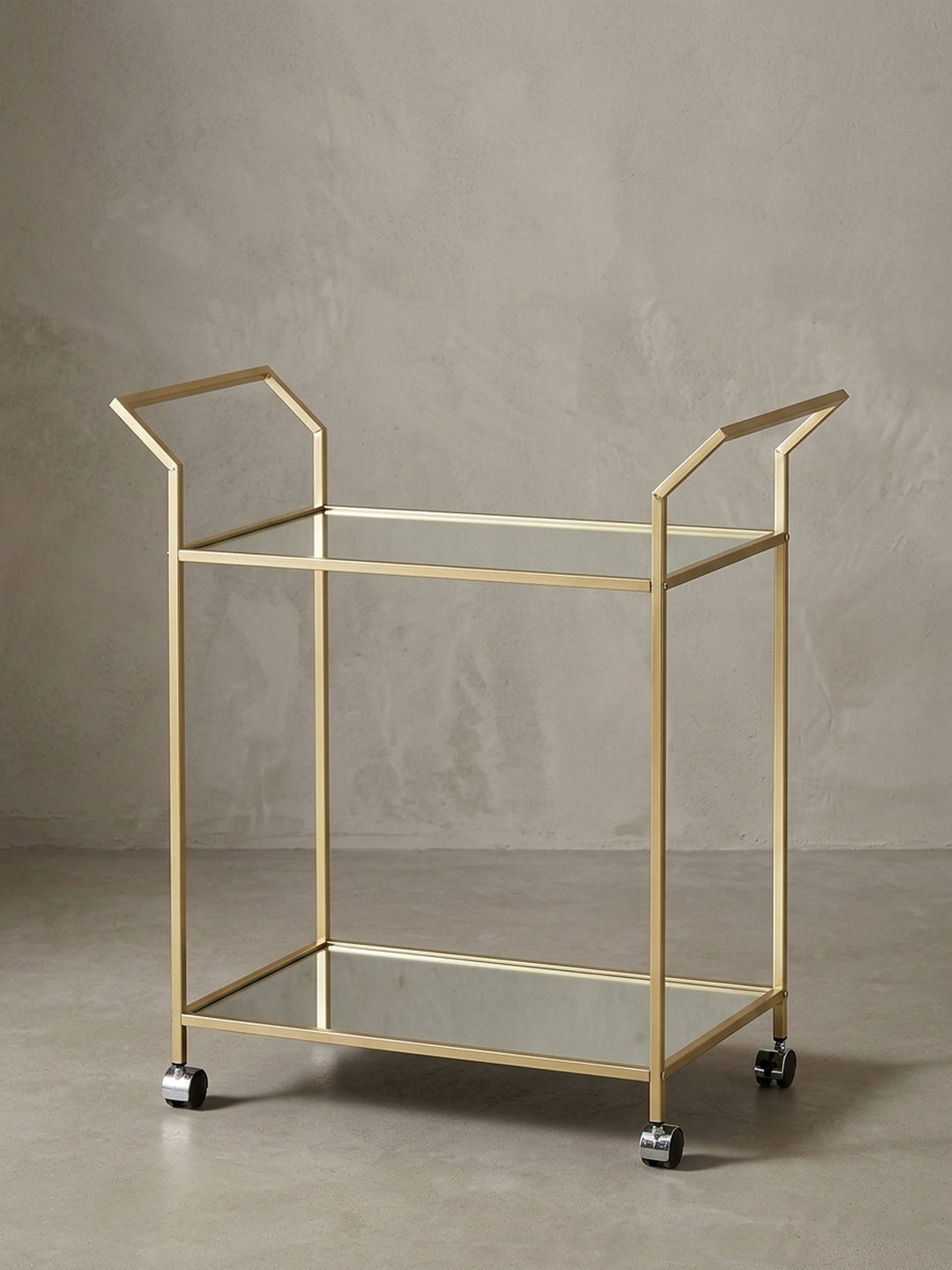 Seitenansicht des Teewagens, die die schlanke Silhouette mit 78 cm Höhe und die filigrane Konstruktion des goldenen Stahlrahmens betont._