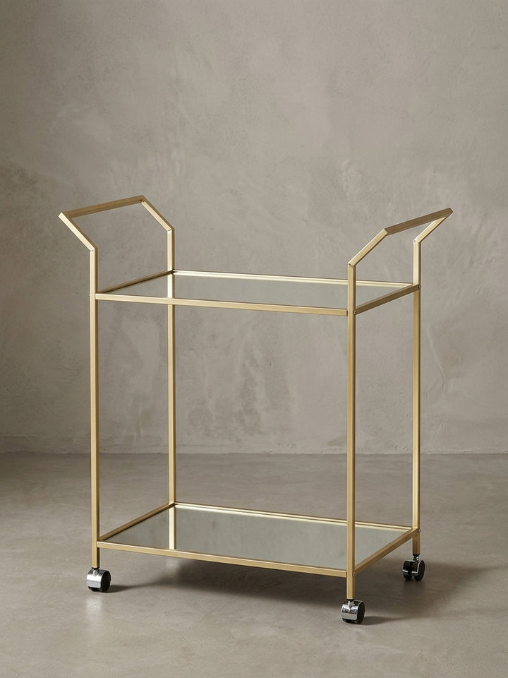 Seitenansicht des Teewagens, die die schlanke Silhouette mit 78 cm Höhe und die filigrane Konstruktion des goldenen Stahlrahmens betont._
