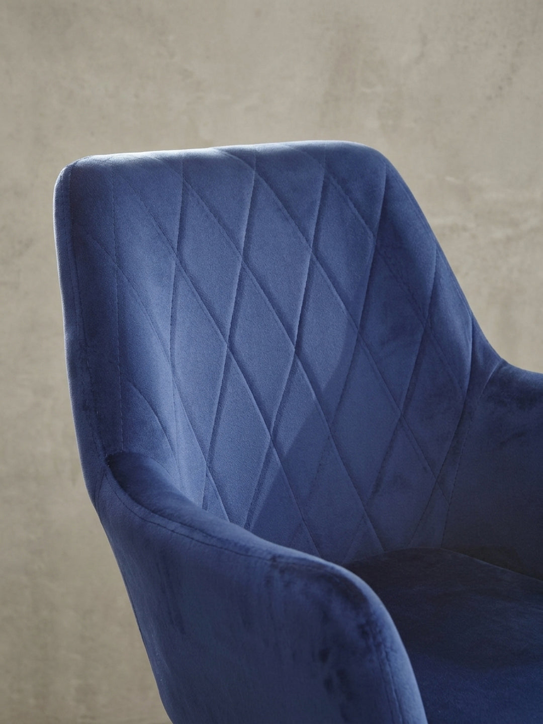 Perspektivische Ansicht des Schreibtischstuhls aus Samt. Die einladende, gepolsterte Sitzfläche und die eleganten Armlehnen werden aus einem alternativen Winkel gezeigt._