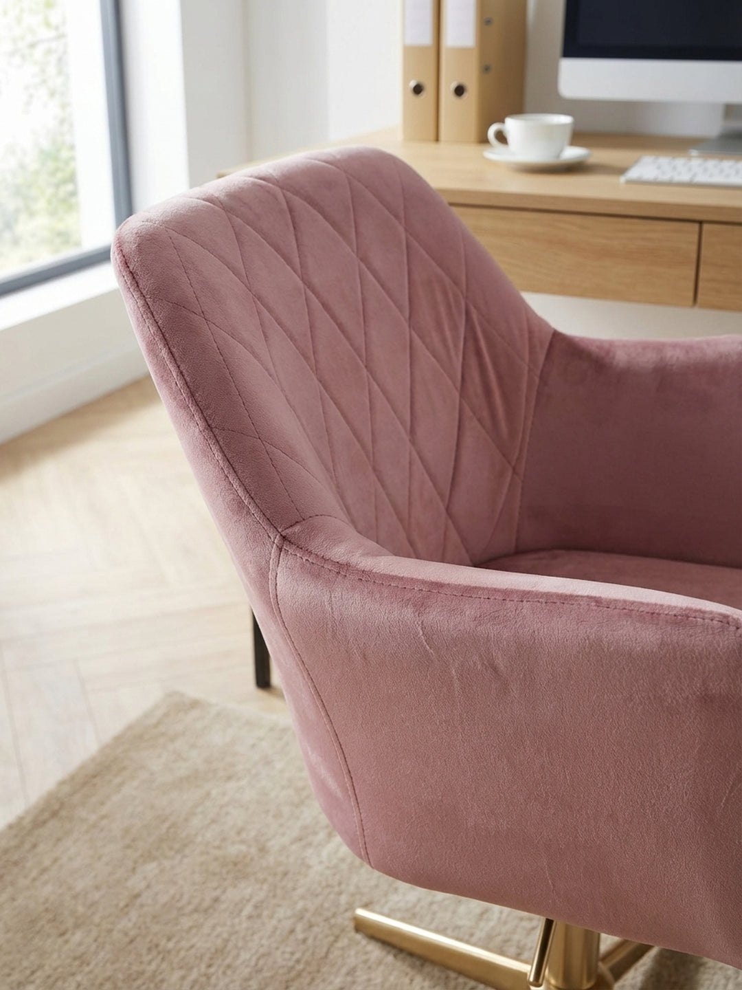 Detailaufnahme der weichen Samt-Oberfläche des rosa Bürostuhls, die feine Rautensteppung der Rückenlehne und die luxuriöse Textur des Stoffes betonend._