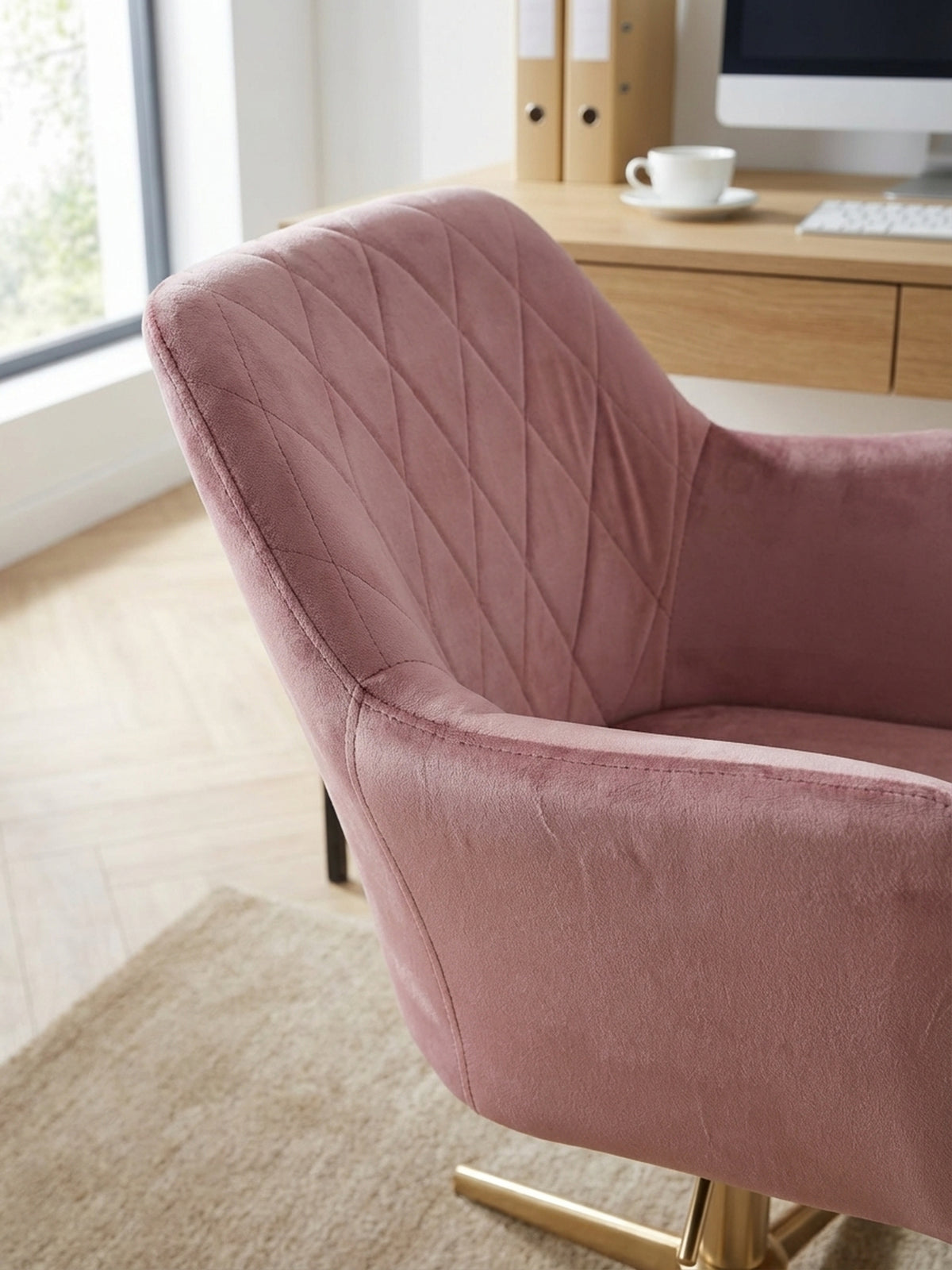 Detailaufnahme der weichen Samt-Oberfläche des rosa Bürostuhls, die feine Rautensteppung der Rückenlehne und die luxuriöse Textur des Stoffes betonend.