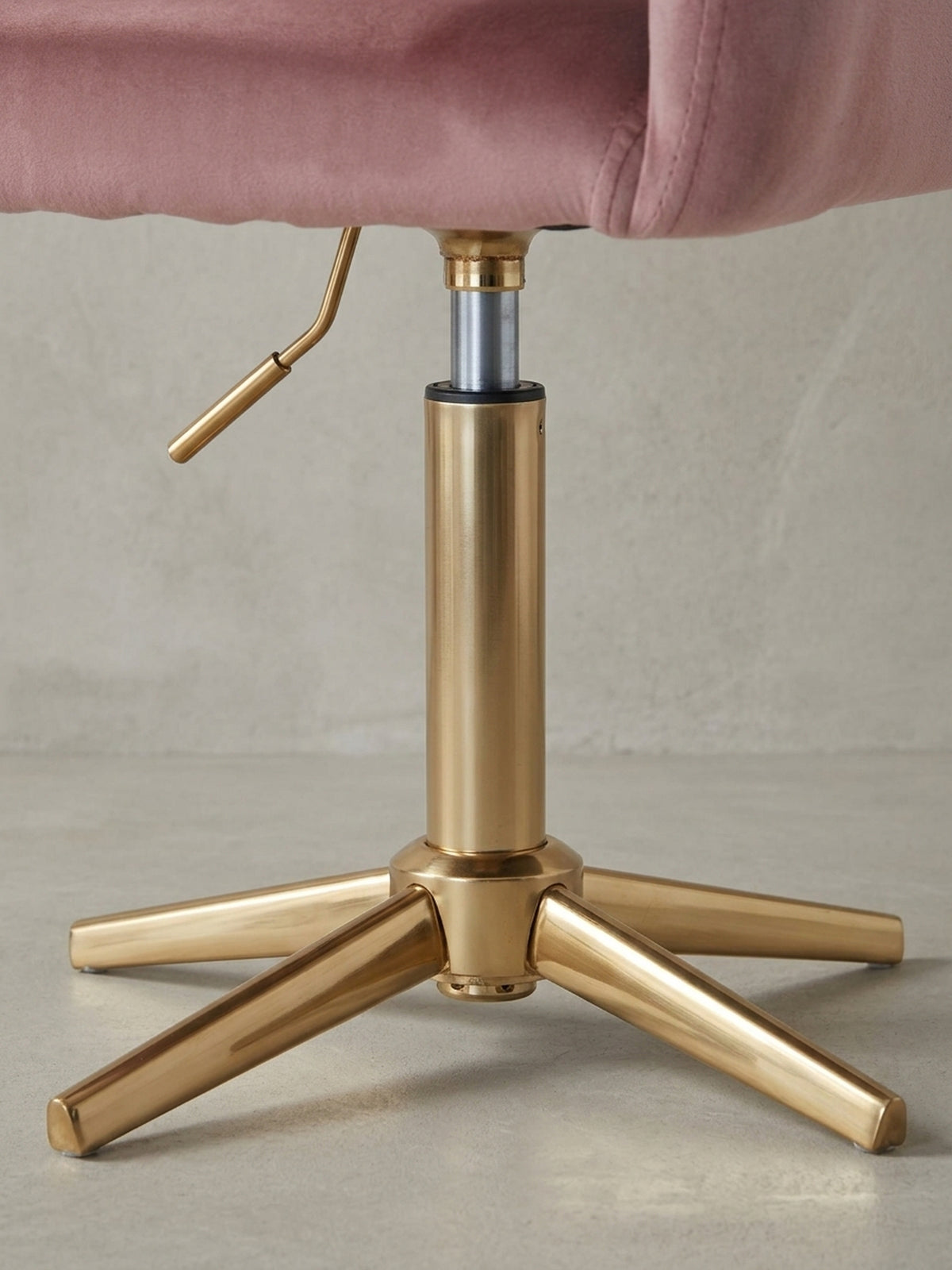 Nahaufnahme des eleganten, goldfarbenen Metallfußes des rosa Drehstuhls, das die hochwertige Verarbeitung und das stabile Vierstern-Design unterstreicht.