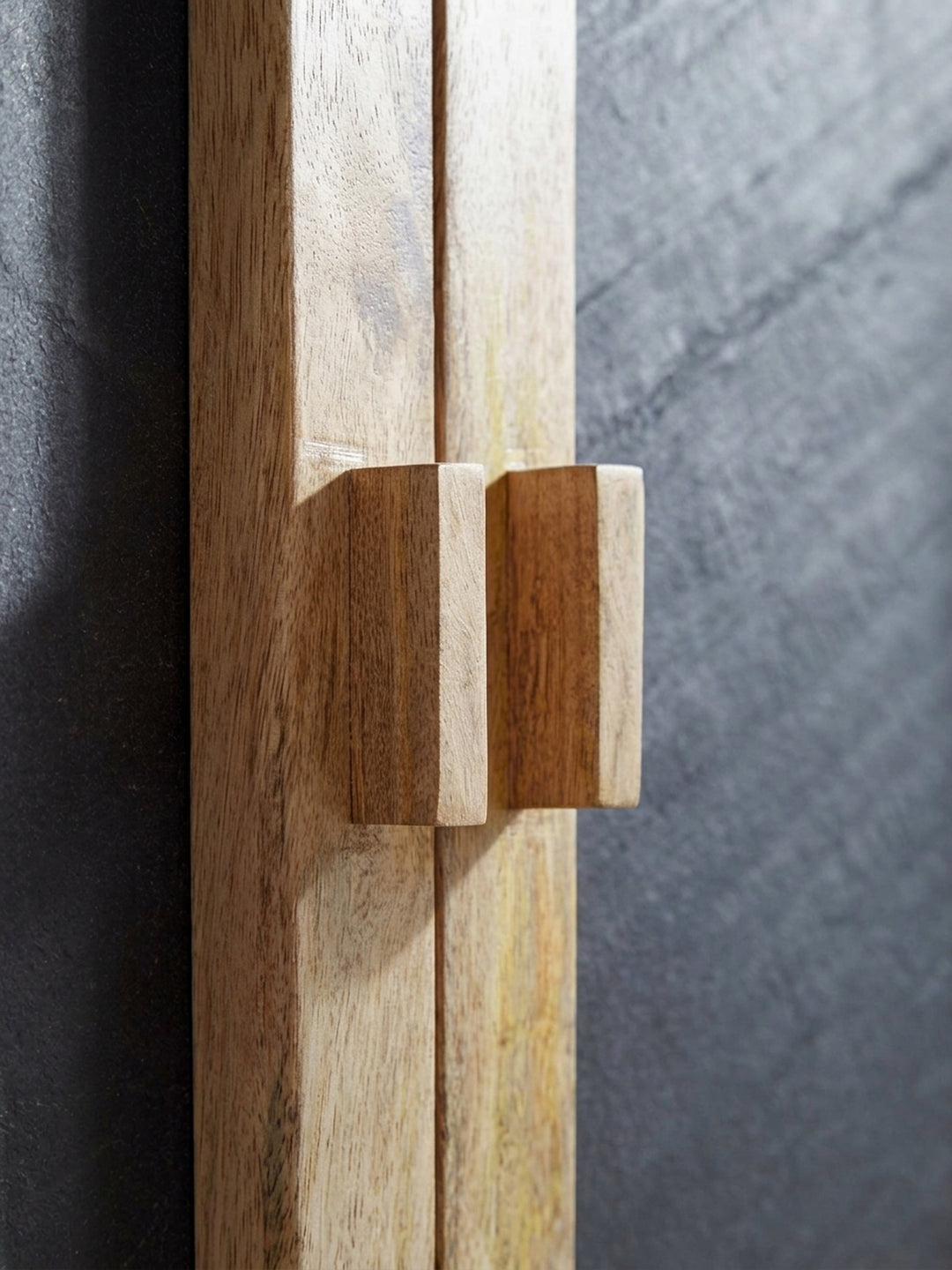 Nahaufnahme der grifflosen Türfront des Sideboards, die die präzise eingearbeiteten Holzgriffe und die fugenlose Verarbeitung des Mangoholzes im Detail sichtbar macht._