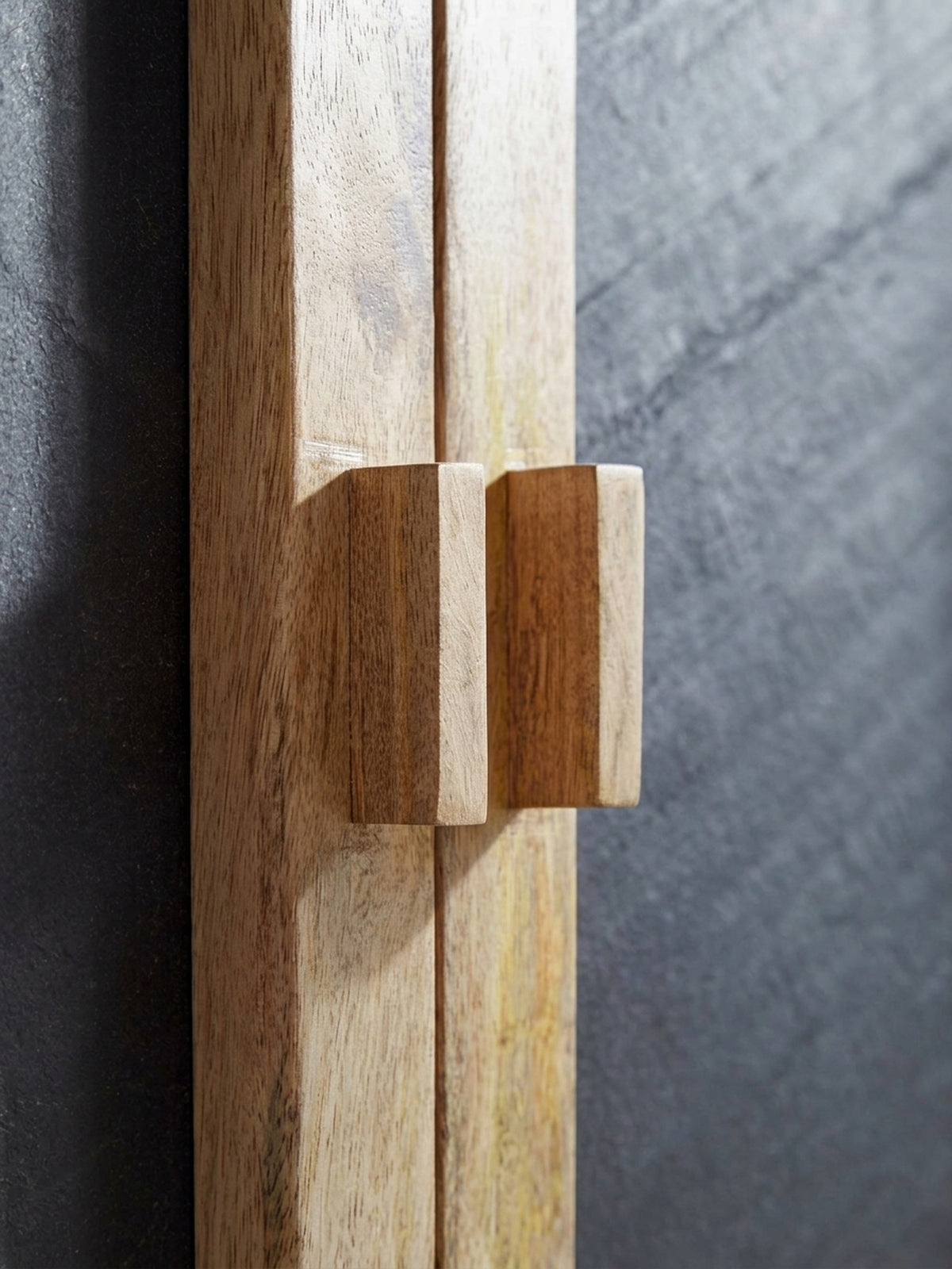 Nahaufnahme der grifflosen Türfront des Sideboards, die die präzise eingearbeiteten Holzgriffe und die fugenlose Verarbeitung des Mangoholzes im Detail sichtbar macht._