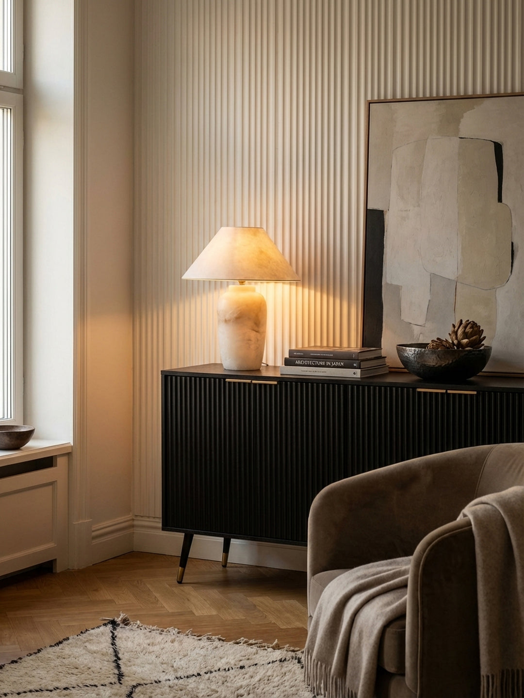 Elegante Anrichte in Schwarz dekoriert mit einer leuchtenden Alabaster-Tischlampe, Kunstbüchern und einer handgeschmiedeten Schale._