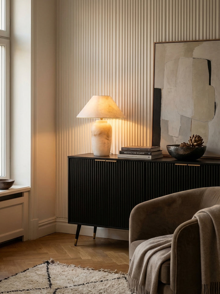 Elegante Anrichte in Schwarz dekoriert mit einer leuchtenden Alabaster-Tischlampe, Kunstbüchern und einer handgeschmiedeten Schale._
