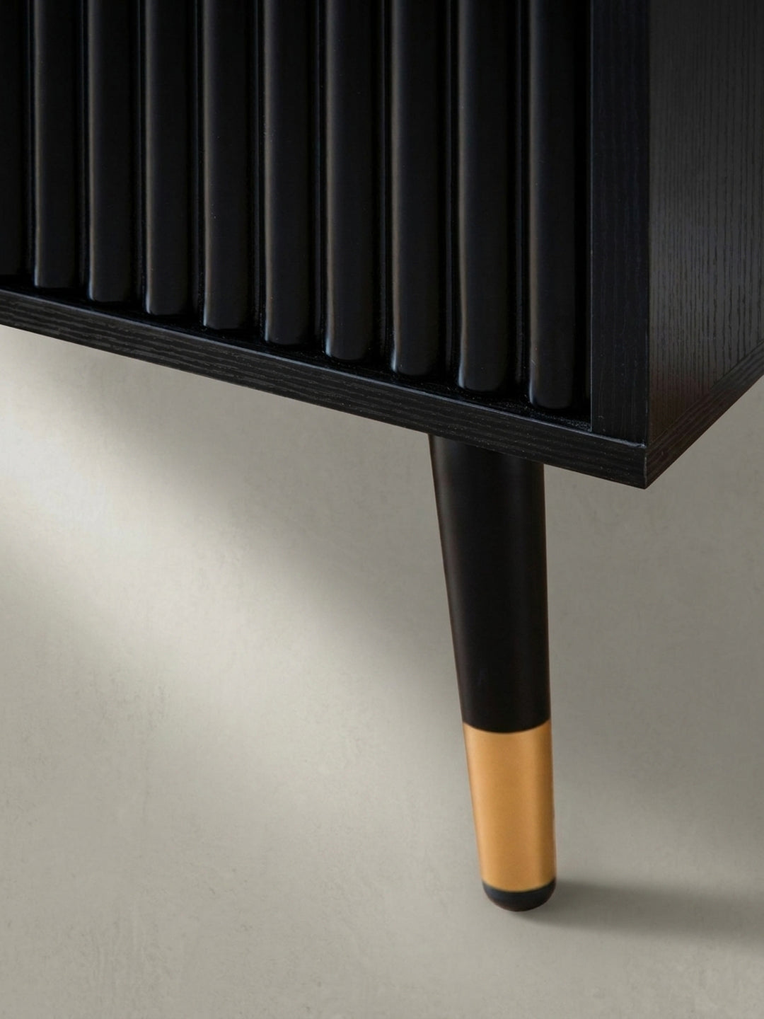 Perspektivische Ansicht des schwarzen Sideboards, die den eleganten Kontrast zwischen der mattschwarzen Oberfläche und den glänzenden Goldgriffen betont._