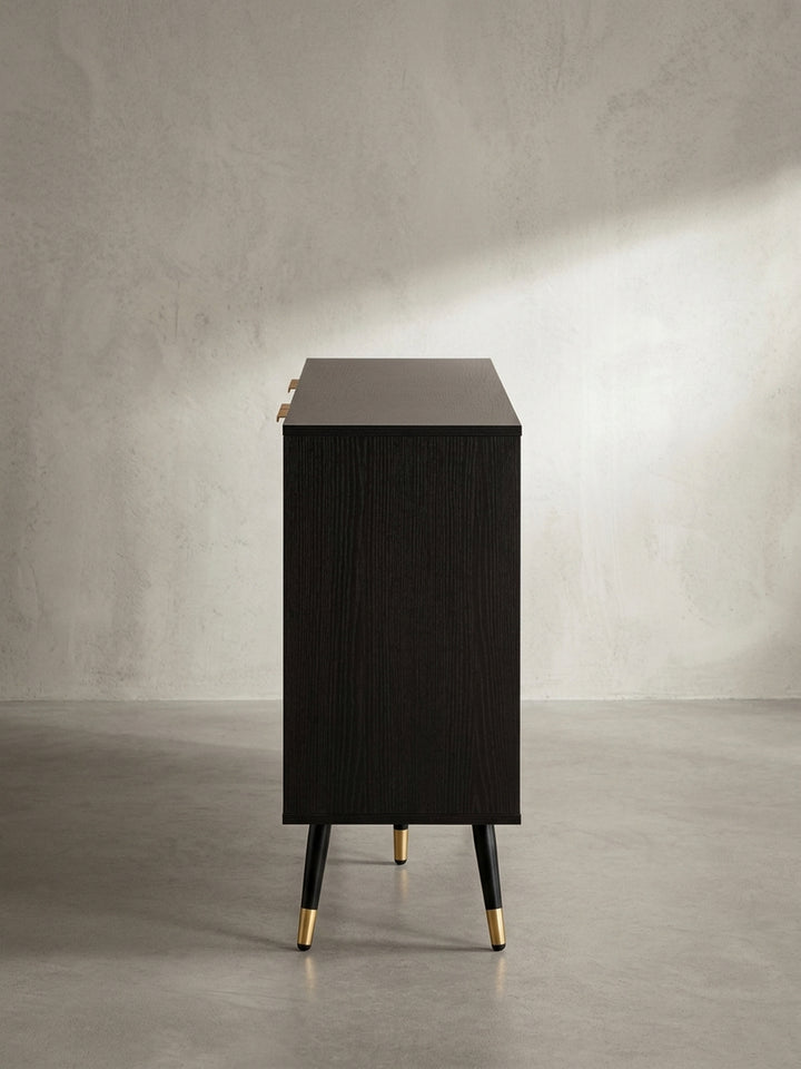 Nahaufnahme eines der goldfarbenen Griffe auf der Lamellentür, die die präzise Verarbeitung und das minimalistische Design des Kommodenschranks zeigt._