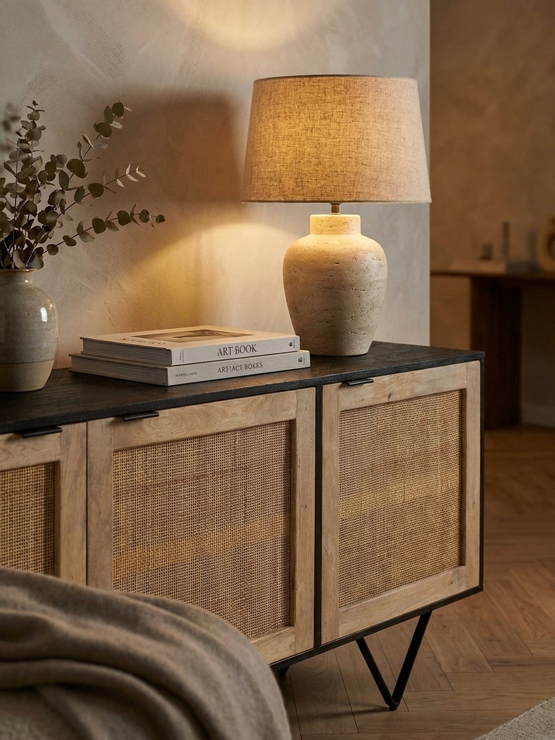 Dekorierte Ablagefläche des schwarzen Holz-Sideboards mit einer schweren Travertinlampe und getrocknetem Eukalyptus im eleganten Flur._