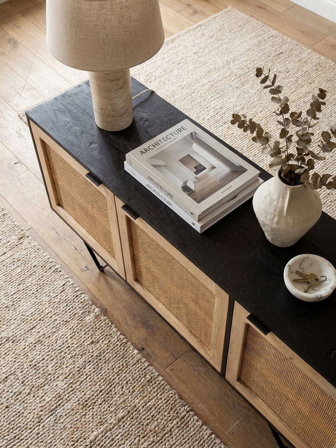 Blick von oben auf das 175 cm breite Rattan Sideboard im organisch modernen Esszimmer, arrangiert mit hellen Textilien und abstrakter Kunst._