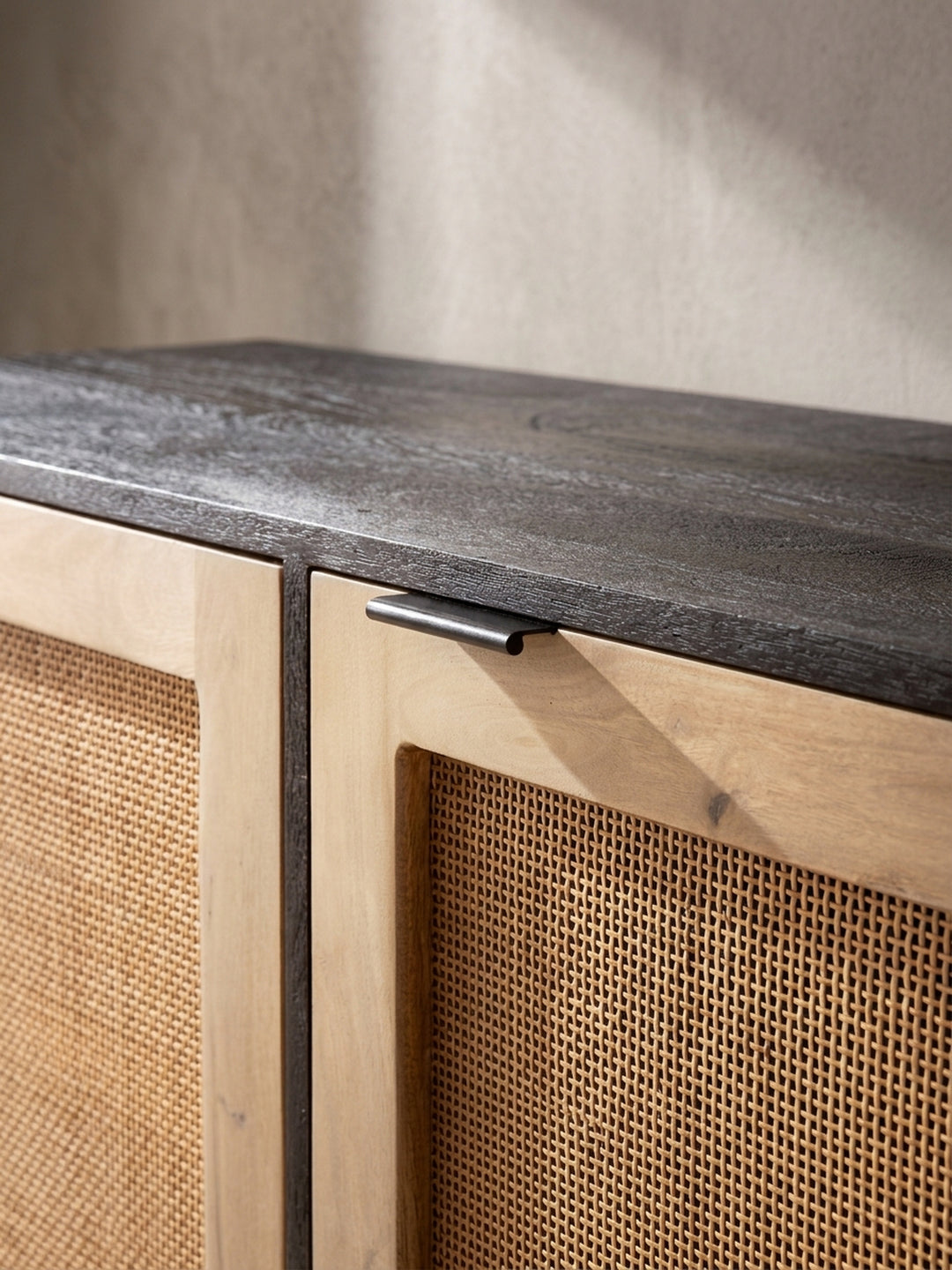 Leicht erhöhte Perspektive auf das Mango Massivholz Sideboard mit Fokus auf das luftige Naturgeflecht der drei Schranktüren._