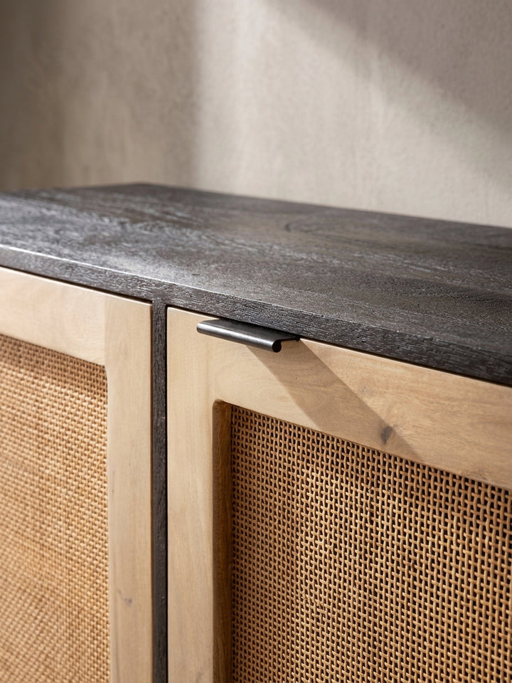 Leicht erhöhte Perspektive auf das Mango Massivholz Sideboard mit Fokus auf das luftige Naturgeflecht der drei Schranktüren._