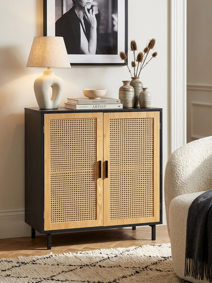 Styling-Detail auf einer schwarzen Anrichte mit Rattan-Türen, dekoriert mit einer Keramikvase und einem Stapel Kunstbücher._