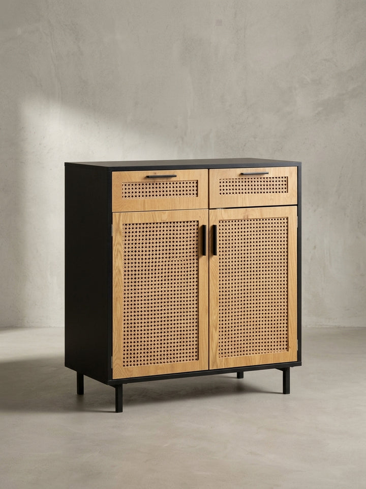 Das Sideboard mit zwei Türen und Schubladen in einer schrägen 3/4-Ansicht, die die Tiefe des schwarzen Korpus und die feine Rattanstruktur zeigt._