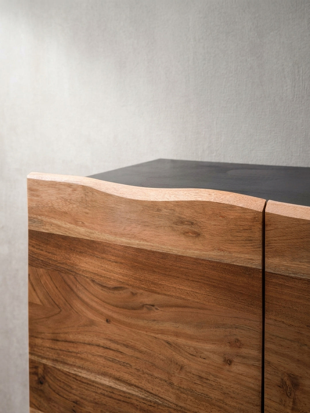 Detailaufnahme der organischen Baumkante an der Oberseite der grifflosen Türen des Sideboards aus massivem Akazienholz._