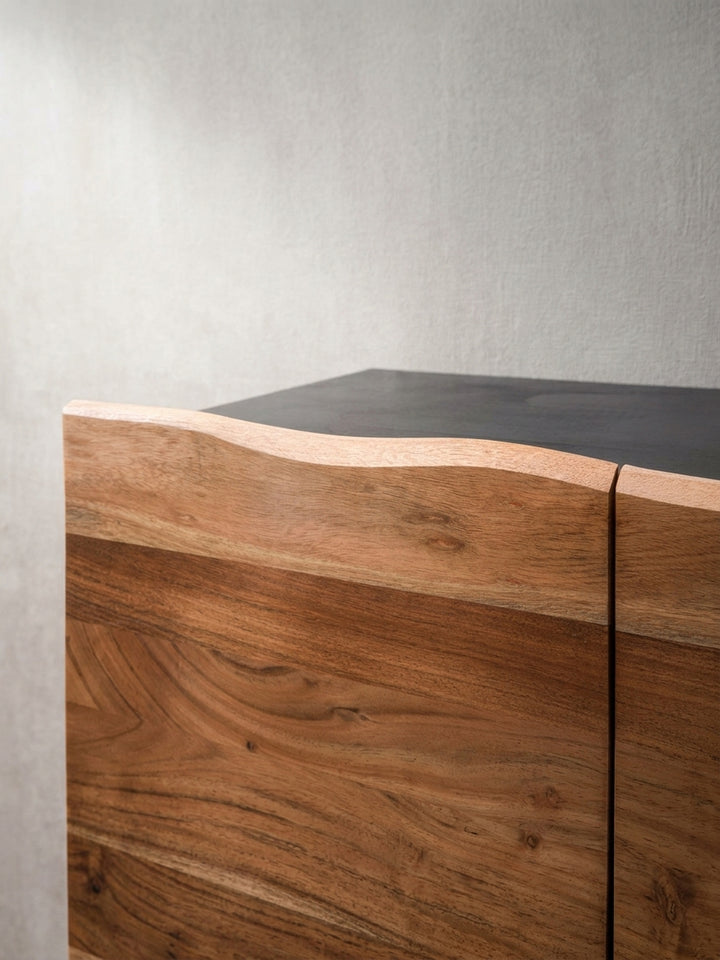Detailaufnahme der organischen Baumkante an der Oberseite der grifflosen Türen des Sideboards aus massivem Akazienholz._