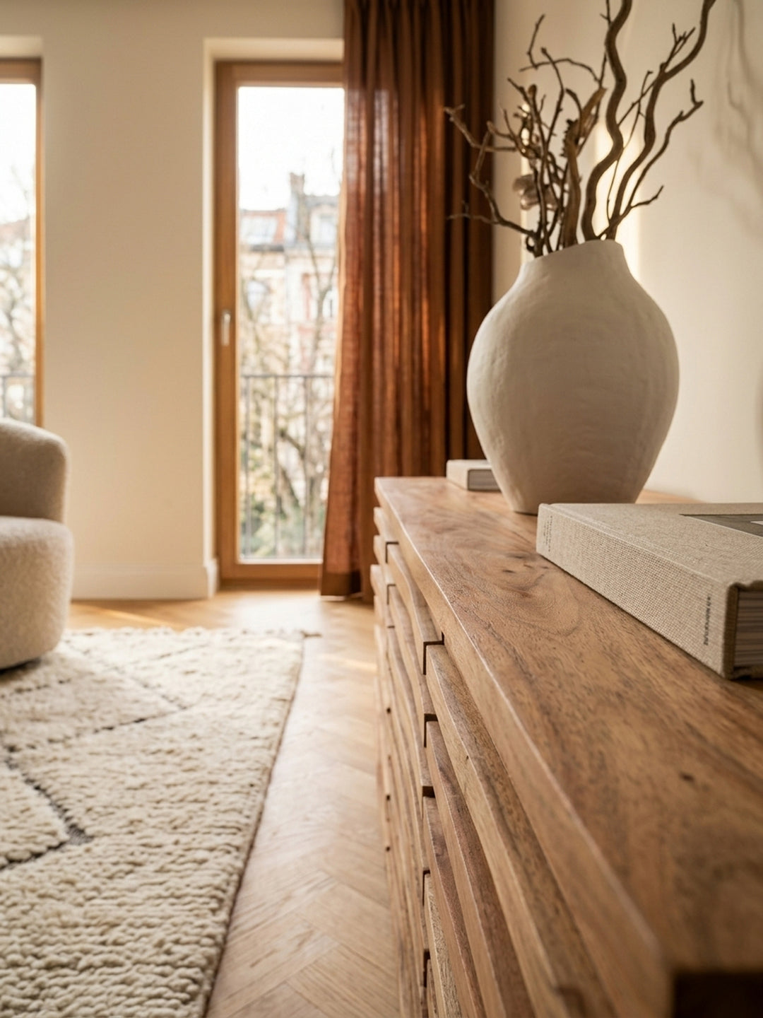 Nahaufnahme der gewellten Holzfront aus massiver Akazie. Die feine Maserung, der warme Naturton und die präzise Verarbeitung der PU-versiegelten Kommode im modernen Landhausstil zeigen._