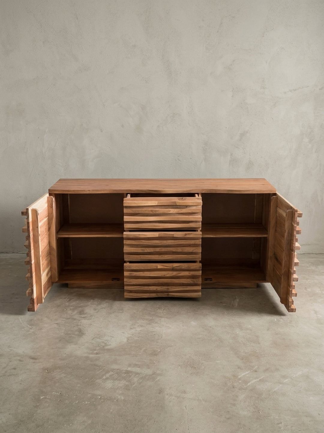 Alternative Perspektive der Holzkommode, die das dynamische Licht- und Schattenspiel auf der wellenförmigen 3D-Front aus naturbelassener massiver Akazie eindrucksvoll hervorhebt._