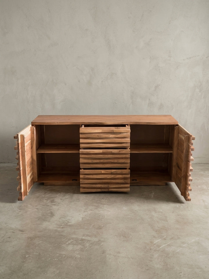 Alternative Perspektive der Holzkommode, die das dynamische Licht- und Schattenspiel auf der wellenförmigen 3D-Front aus naturbelassener massiver Akazie eindrucksvoll hervorhebt._
