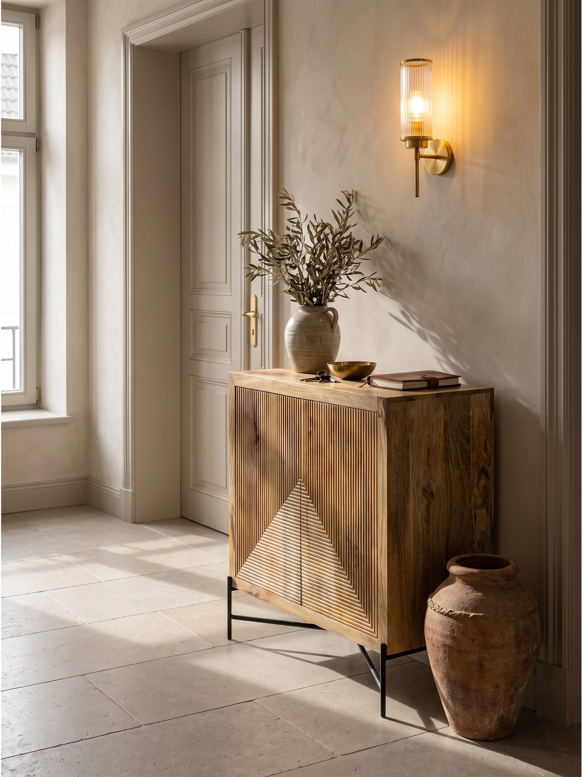 Das Massivholz-Sideboard als stilvolle Fluranrichte kombiniert mit einer großen Terrakotta-Urne auf mattem Kalksteinboden_
