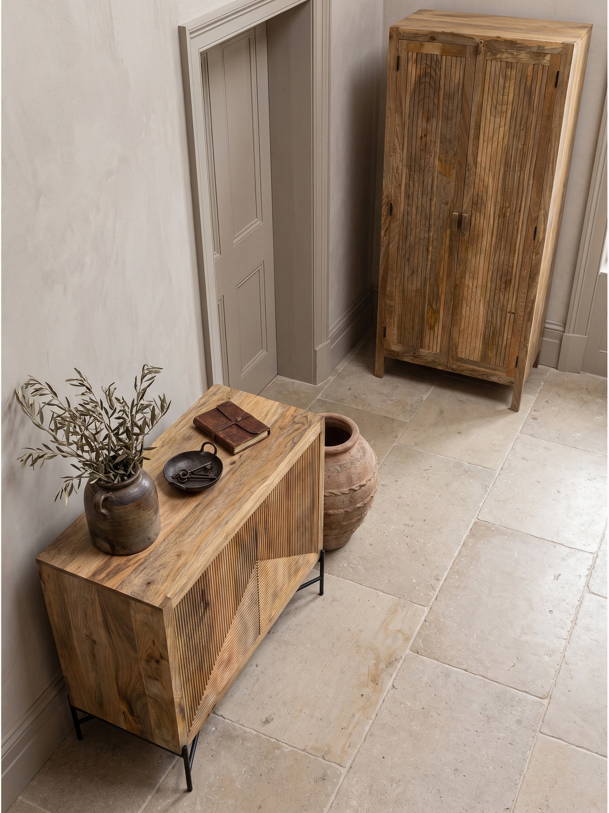 Draufsicht auf das handgefertigte Holz-Sideboard mit geometrischer Rillenfront im modernen Eingangsbereich neben einer Keramikvase_